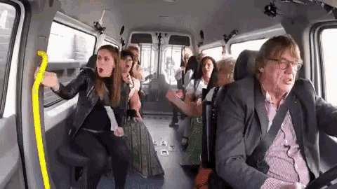 a man in a suit is driving a van with a bunch of people in it