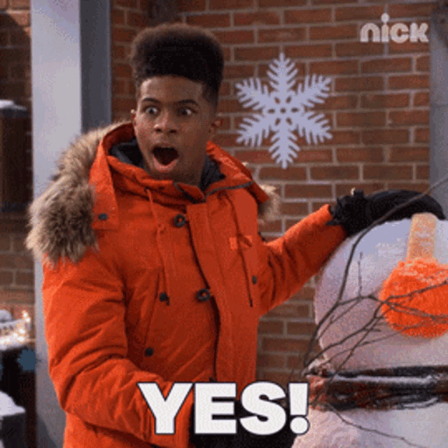 a man in an orange jacket stands next to a snowman and says " yes "