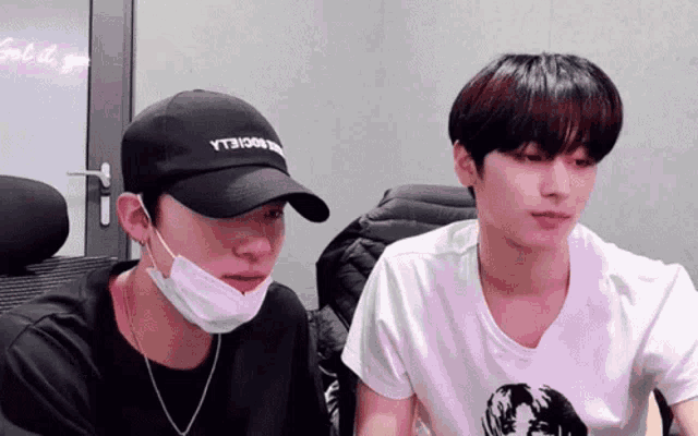 two men wearing face masks and hats are sitting next to each other