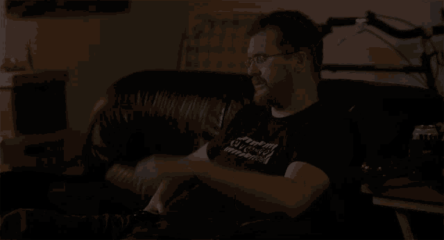 a man sitting on a couch wearing a black shirt that says " i love you " on it