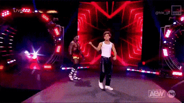 a man in a white tank top is dancing on a stage .