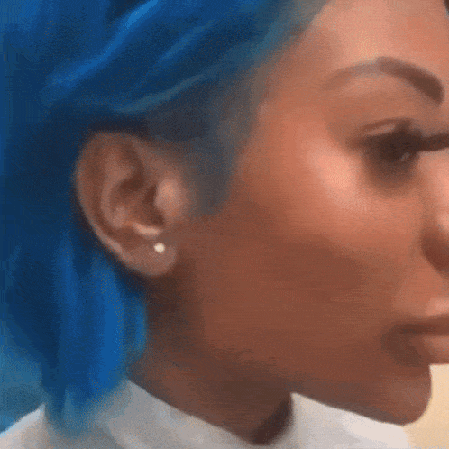 a woman with blue hair is wearing earrings and a white shirt .