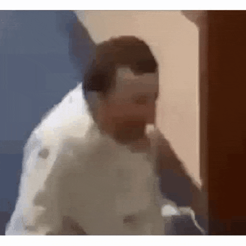 a man is standing in a room talking on a phone .