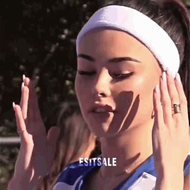 a woman wearing a headband and a ring is covering her ears .