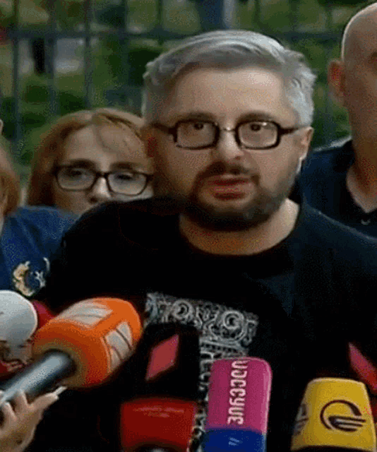 a man with glasses and a beard is speaking into a microphone that says bbc