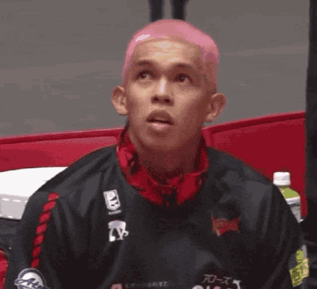 a man with pink hair is wearing a black and red jacket with a logo for tokyo
