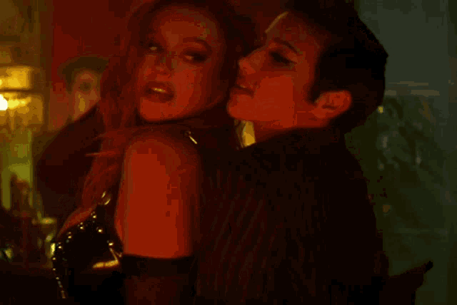 a woman with red hair is kissing a man in a striped shirt .