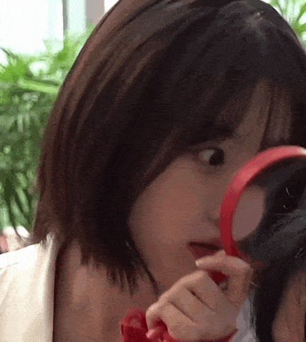 a woman is looking through a magnifying glass at herself .