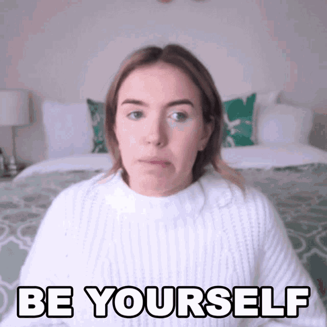 a woman wearing a white sweater says " be yourself "