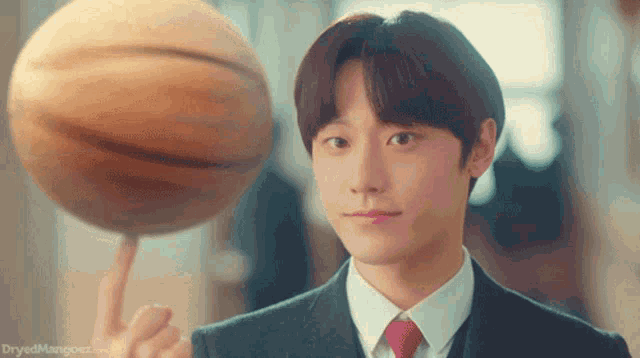a man in a suit is holding a basketball on his finger