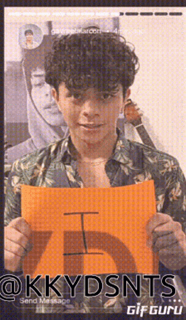 a man with curly hair is holding a sign that says i on it