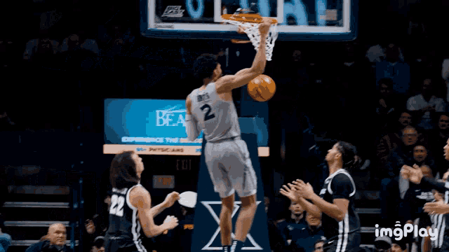 a basketball player with the number 2 on his jersey goes for a dunk