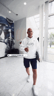 a man wearing a white nike hoodie is walking through a hallway