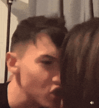 a man and a woman are kissing in front of a curtain .