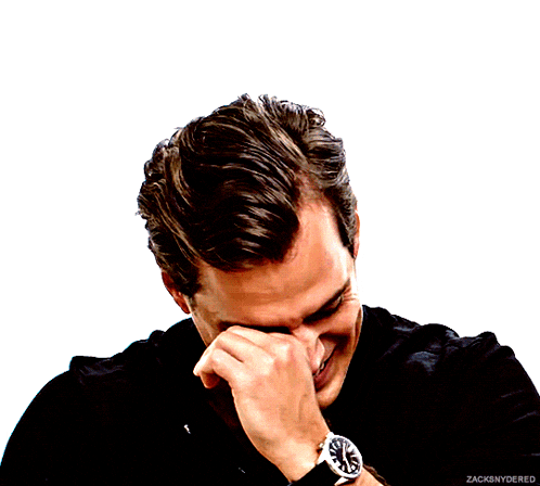 a man wearing a black shirt and a watch covering his face with his hand