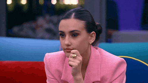 a woman wearing a pink jacket and a gold ring