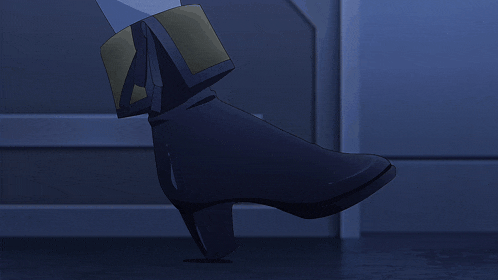 a person wearing a pair of black boots with a gold buckle