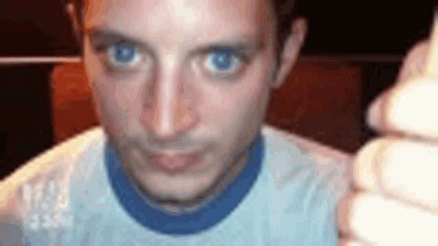a close up of a man 's face with blue eyes wearing a white shirt and a blue collar .