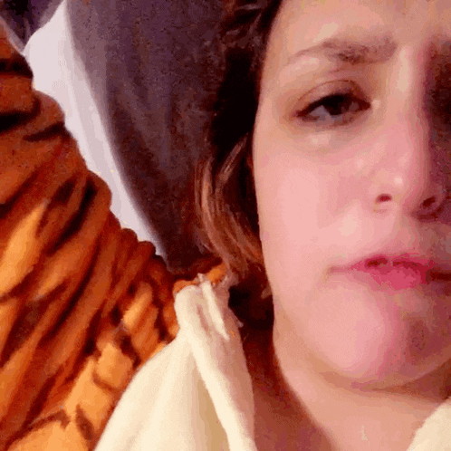 a close up of a woman 's face in front of a tiger print blanket