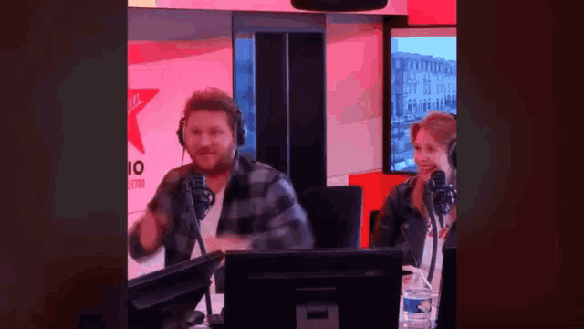a man and a woman are sitting in front of microphones in a radio studio