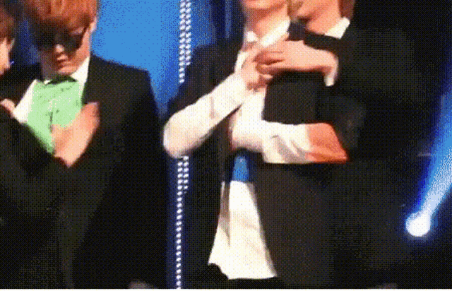 a man in a suit and tie is hugging another man in a green shirt