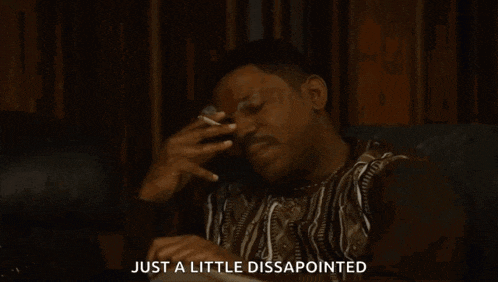 a man is smoking a cigarette while sitting on a couch and says `` just a little disappointed '' .