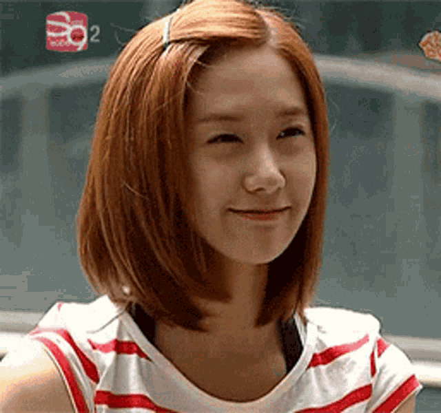 a woman with red hair is smiling and wearing a striped shirt with the number 92 on it