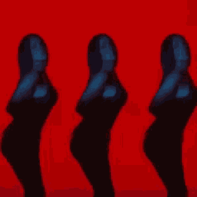 three women are dancing in front of a red backdrop