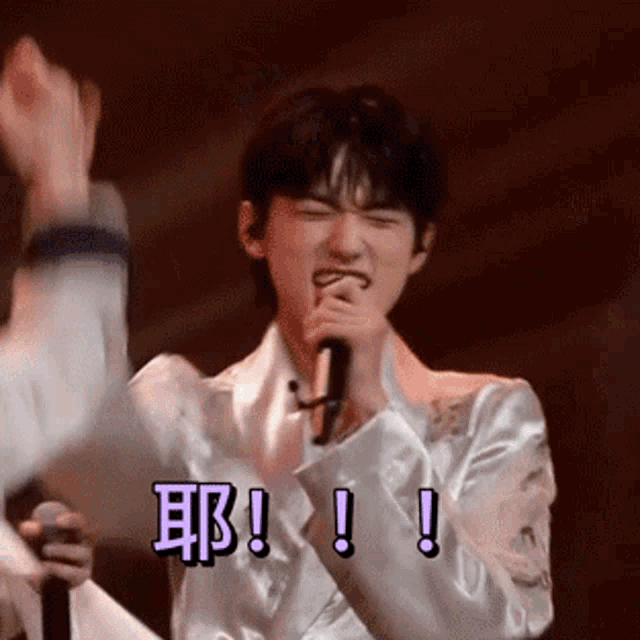 a man in a white jacket is singing into a microphone while holding a microphone .