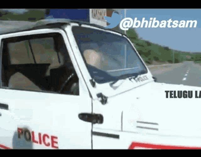 a white police car is driving down the road