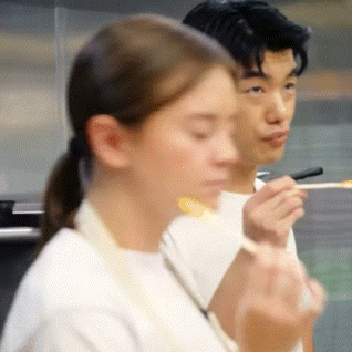 a man and a woman are eating food with chopsticks