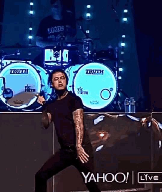 a man singing into a microphone in front of a drum set that says truth on it