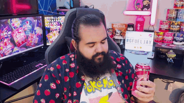 a man with a beard wearing a pokemon shirt holds a can of soda