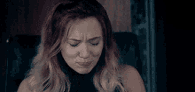 a woman is covering her face with her hands and crying .