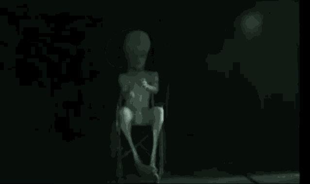 a statue of an alien is sitting in a wheelchair in the dark