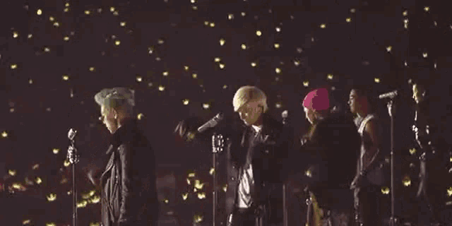 a group of people are standing on a stage with microphones .