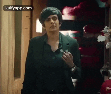 a woman in a black suit is walking down a hallway holding a key .