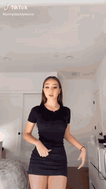 a woman in a black dress is standing in a room with a white door .