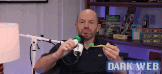 a man is holding a toothbrush in front of a microphone with the words dark web on the bottom right