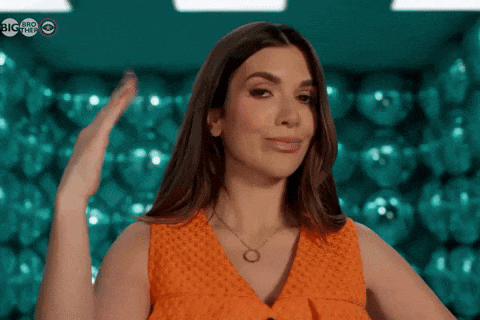 a woman in an orange top is giving a high five in front of a wall of disco balls and a big talk logo