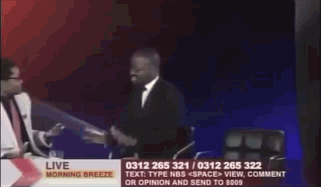 a man in a suit is talking to another man on a live morning breeze program
