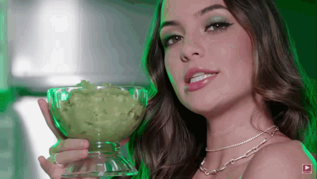 a woman is holding a bowl of guacamole in front of her face