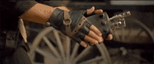 a person wearing leather gloves is holding a gun in their hand