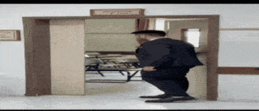 a man in a suit is walking through a doorway with a sign on the wall that says " e-office "