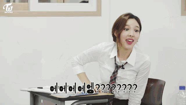a group of girls are sitting at desks in a classroom with twice written on the bottom left
