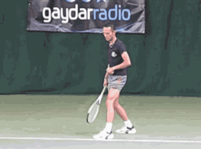 a man holding a tennis racquet on a tennis court in front of a gaydarradio banner