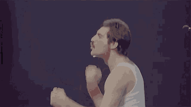 a man with a mustache is wearing a white tank top and wristbands .