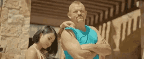 a woman is standing next to a man with his arms crossed .