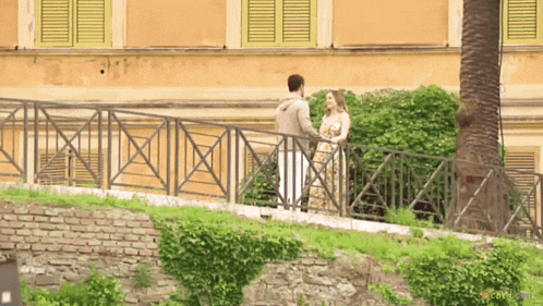 a man and a woman are standing next to a fence and talking