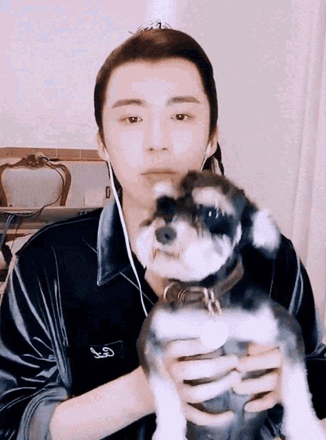 a man holding a small black and white dog with a collar that has the letter g on it